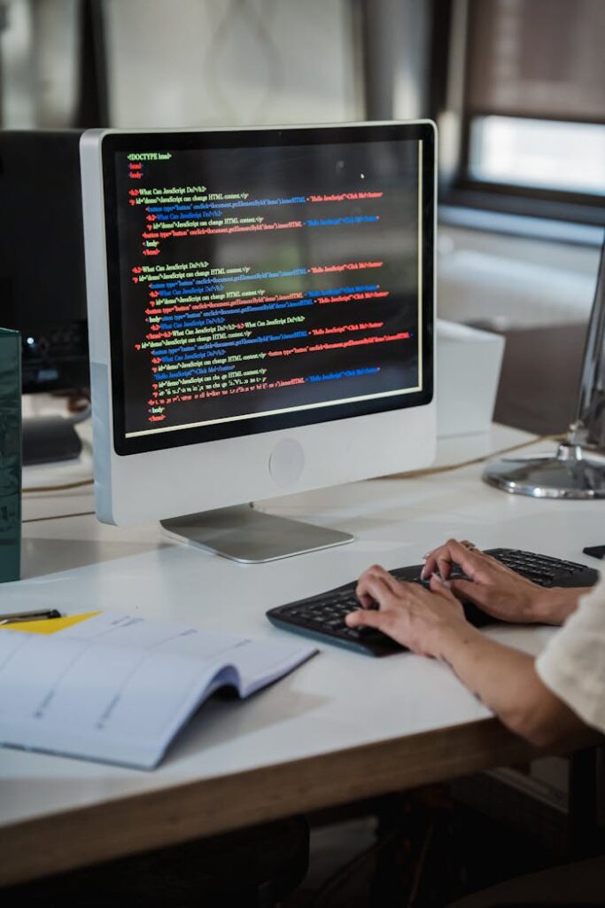 Vertical Shot of Woman Writing on Computer in an Office and Colour Code on a Computer Screen